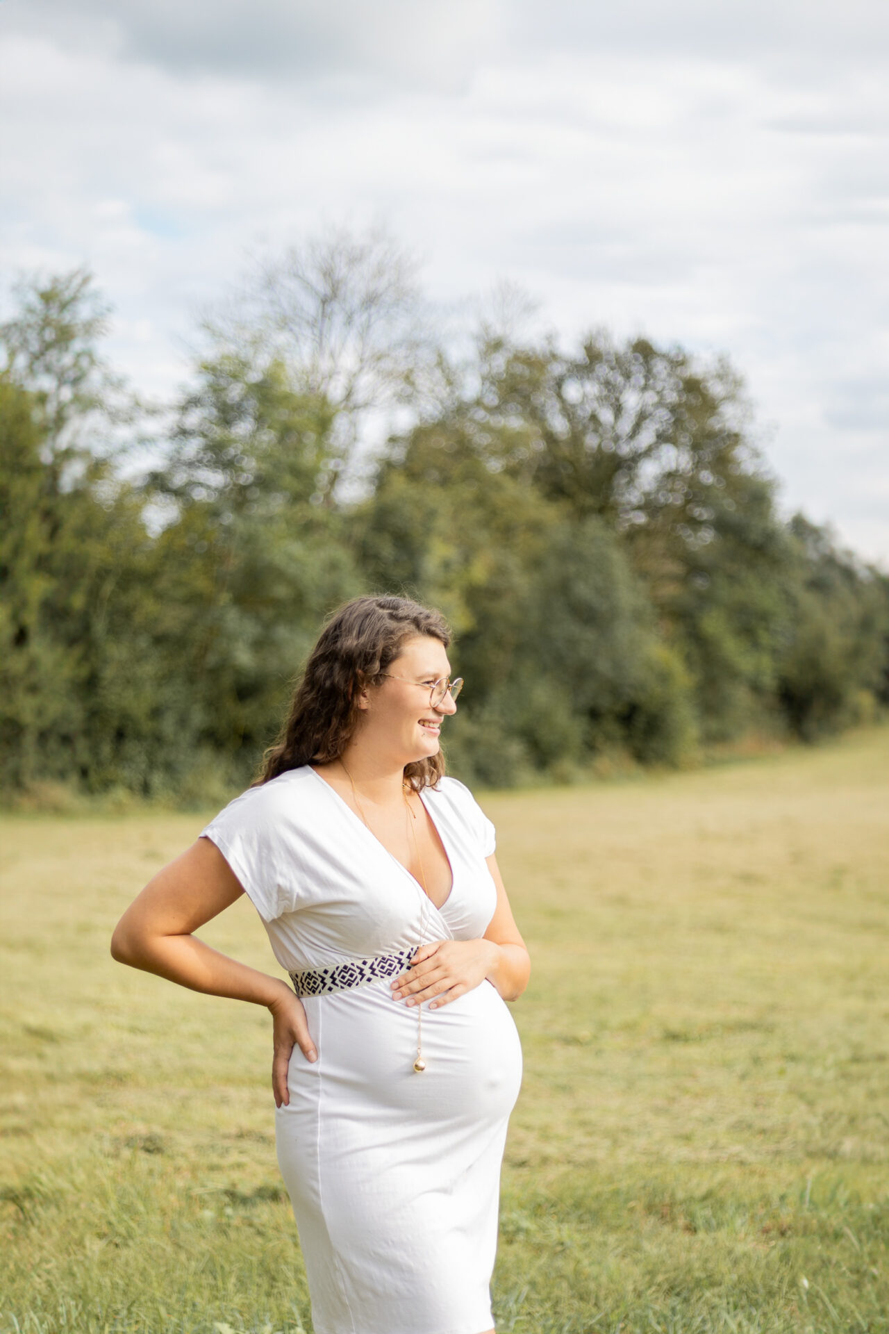 Future maman en robe fluide, photographiée en lumière naturelle par une photographe grossesse à Péronnas (Ain)