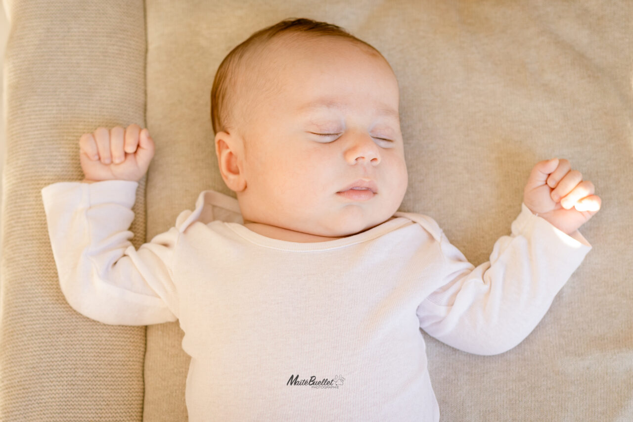 Bébé en body blanc, calme et paisible, photographié en lumière naturelle par une photographe Nouve-né (bébé) à Péronnas (Ain)